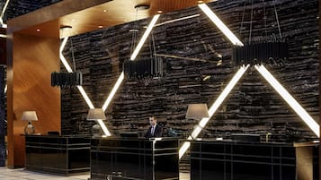 Ein moderner Empfangstresen mit Marmorwand und geometrischen Lichtelementen.