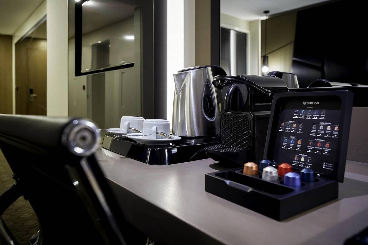 Een Nespresso koffiemachine met een menuscherm, een waterkoker en een bekerhouder met wegwerpbekers.