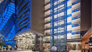 Een modern interieur met een glazen atrium, hoge plafonds en een centrale kolom.