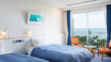 Una habitación de hotel con dos camas, un balcón con vistas y una pequeña mesa con sillas.