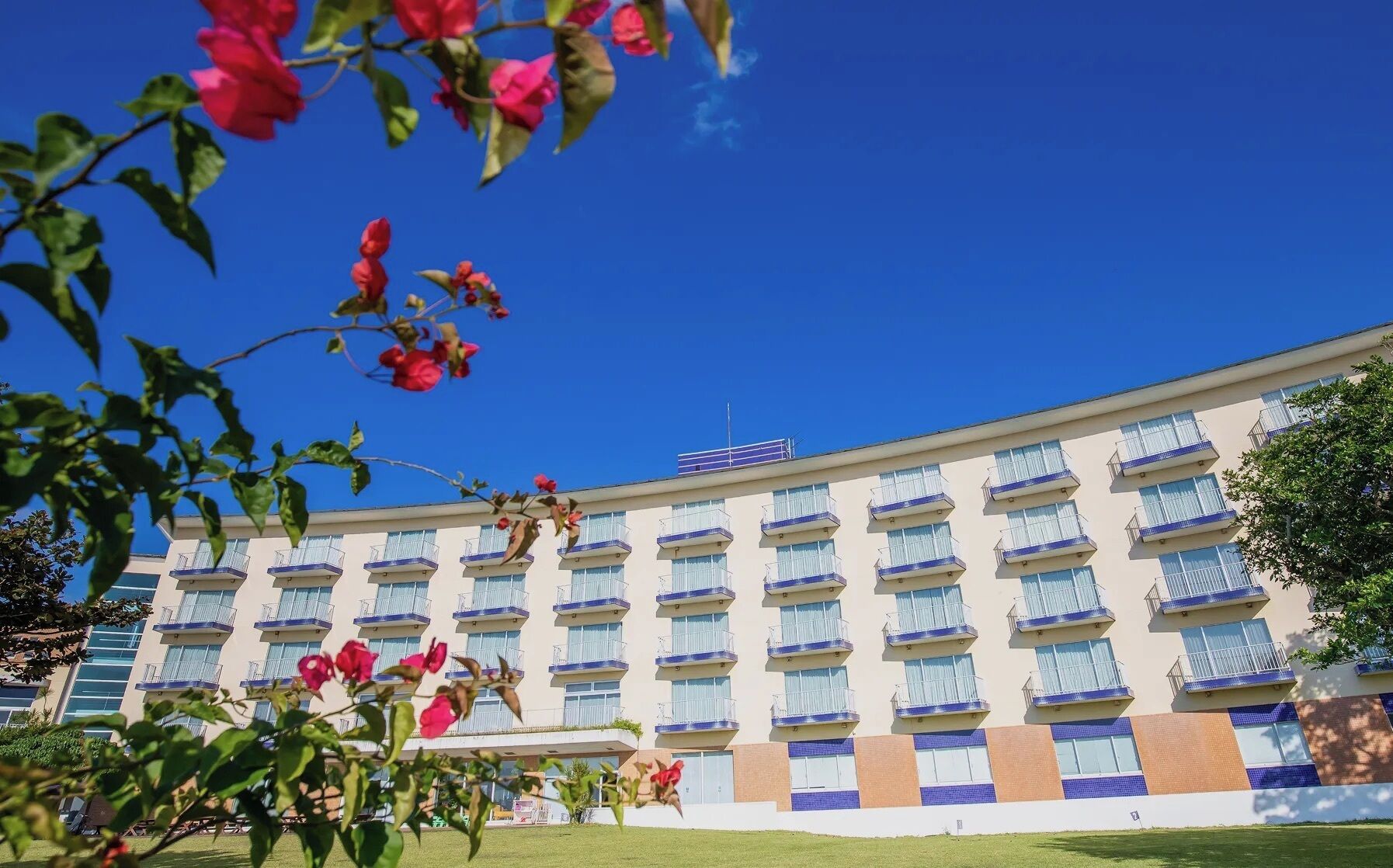 A multi-story hotel with balconies, a flat roof, and a clear blue sky.