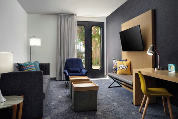 A modern hotel room with a sofa, armchair, desk, and ottoman. - Aloft by Marriott El Segundo - Los Angeles Airport (El Segundo)