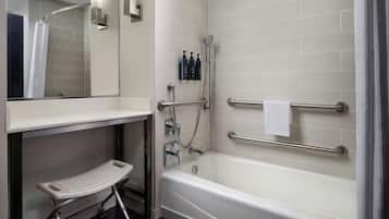 A modern bathroom with a bathtub, a shower, a vanity with a mirror, and a step stool.