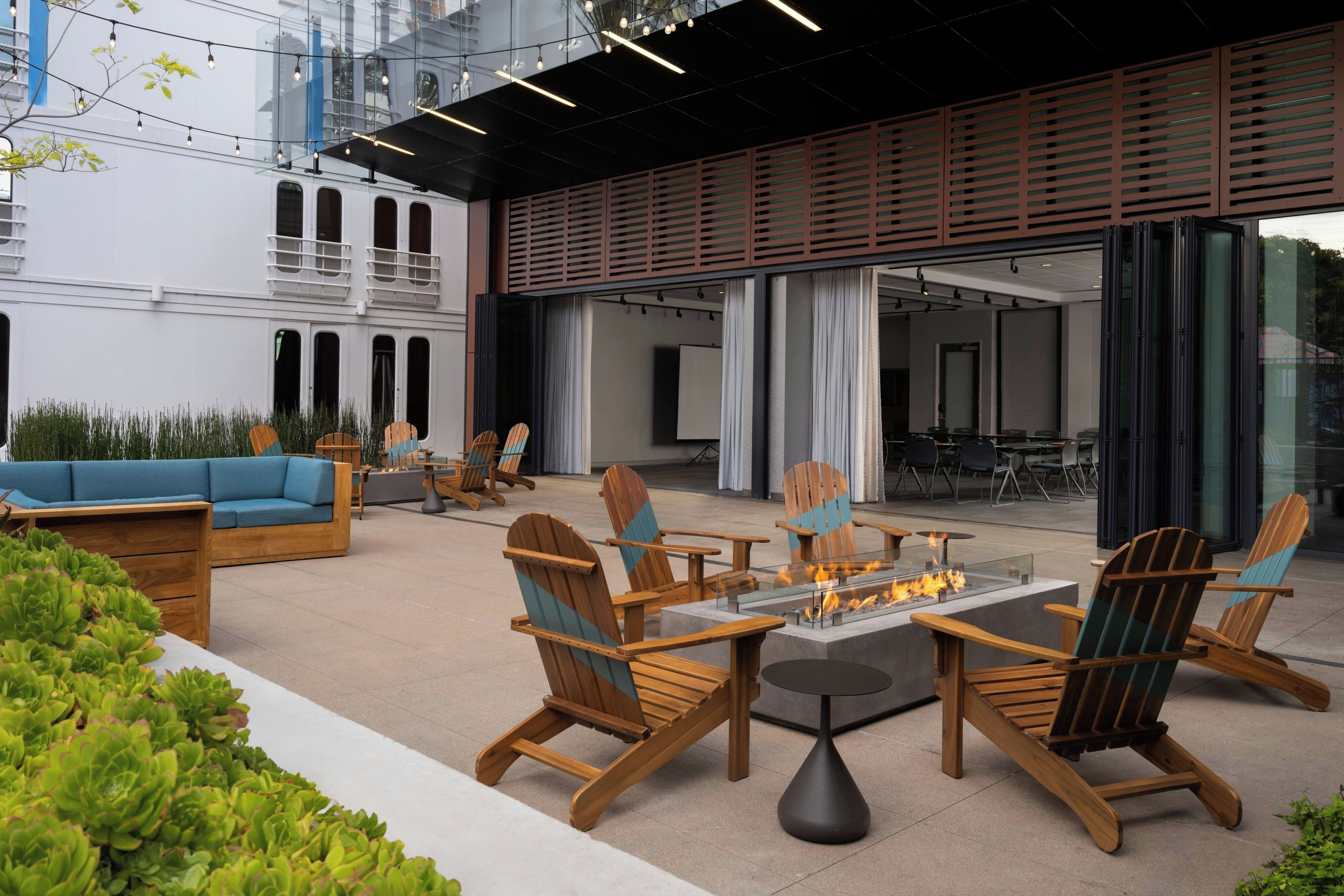 An outdoor seating area with wooden chairs and a central fire feature.