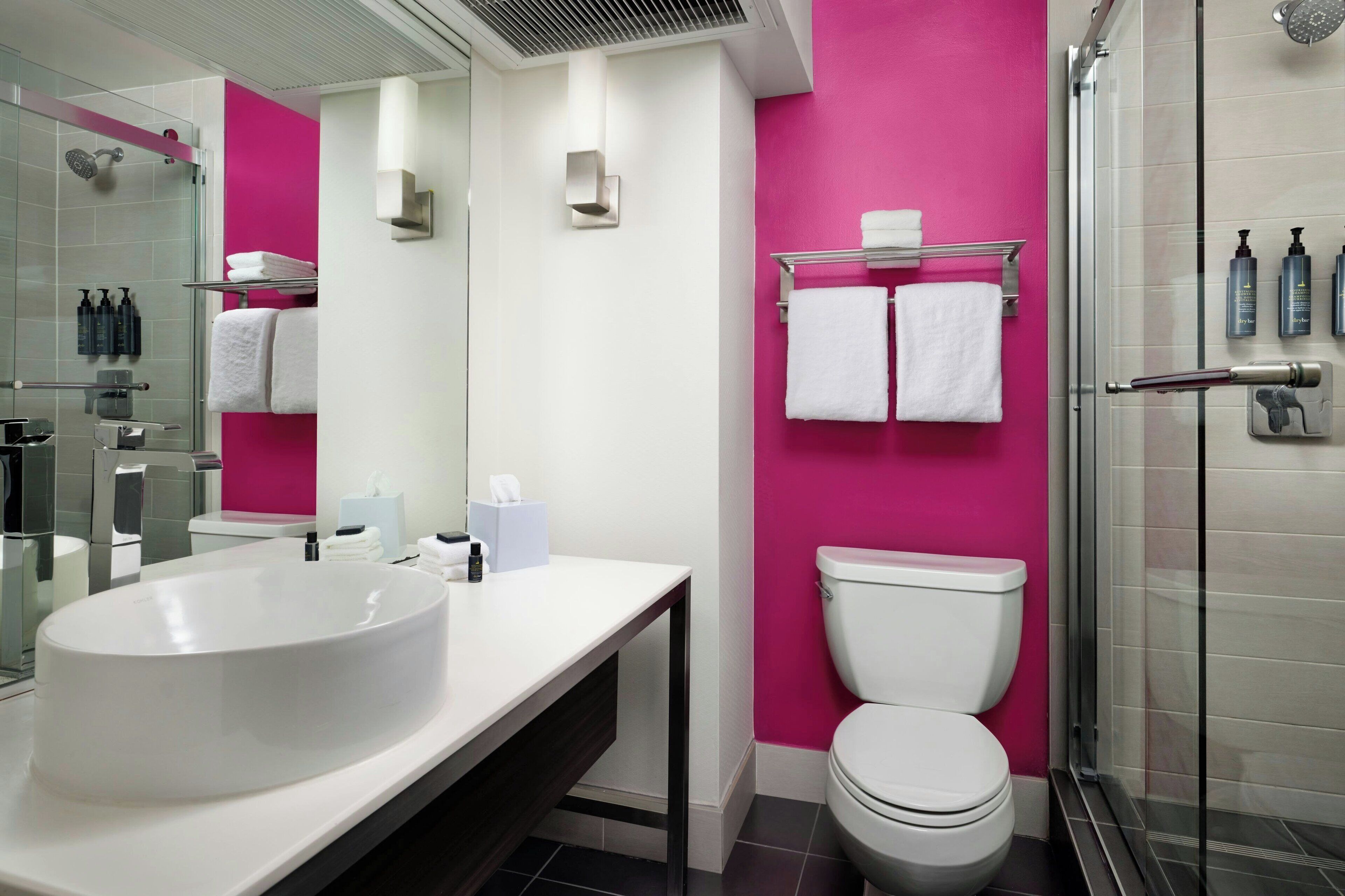 A modern bathroom with a large white sink, a toilet, and a glass-enclosed shower.