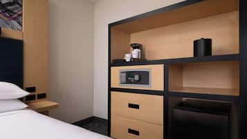 Une chambre d’hôtel équipée d’un lit, d’un minibar, d’une machine à café et d’un panneau de commande.