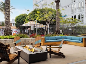 An outdoor seating area with a fire pit, wooden chairs, and a blue sofa.