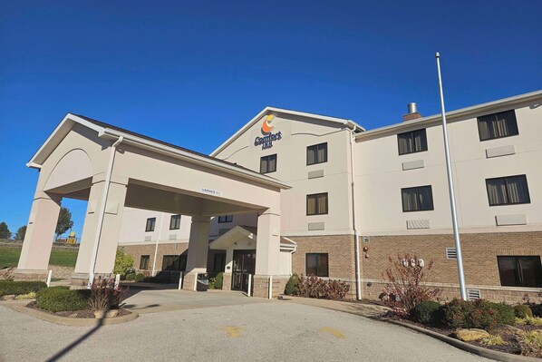 A Comfort Inn hotel with a covered entrance, a clear sky, and a parking lot.