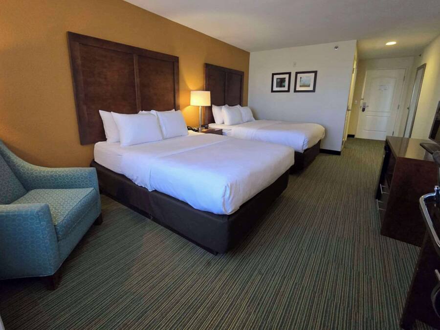A hotel room with two beds, a sofa, a desk, and a television.