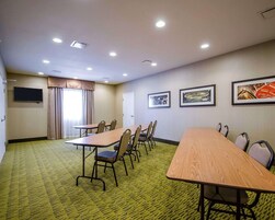 Un salón de conferencias con una larga mesa y sillas, un televisor en la pared y cuadros enmarcados.