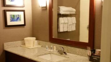 A bathroom with a large mirror, two sinks, a towel rack, and framed pictures on the wall.