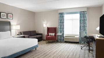 Una habitación de hotel con una cama grande, un escritorio, una silla, un sofá y una mesita.