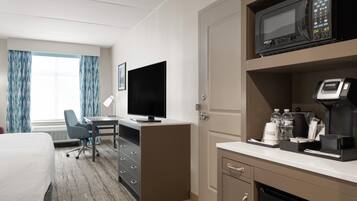Une chambre d’hôtel équipée d’un lit, d’un bureau, d’une télévision, d’un four à micro-ondes, d’une machine à café et d’un mini-bar.