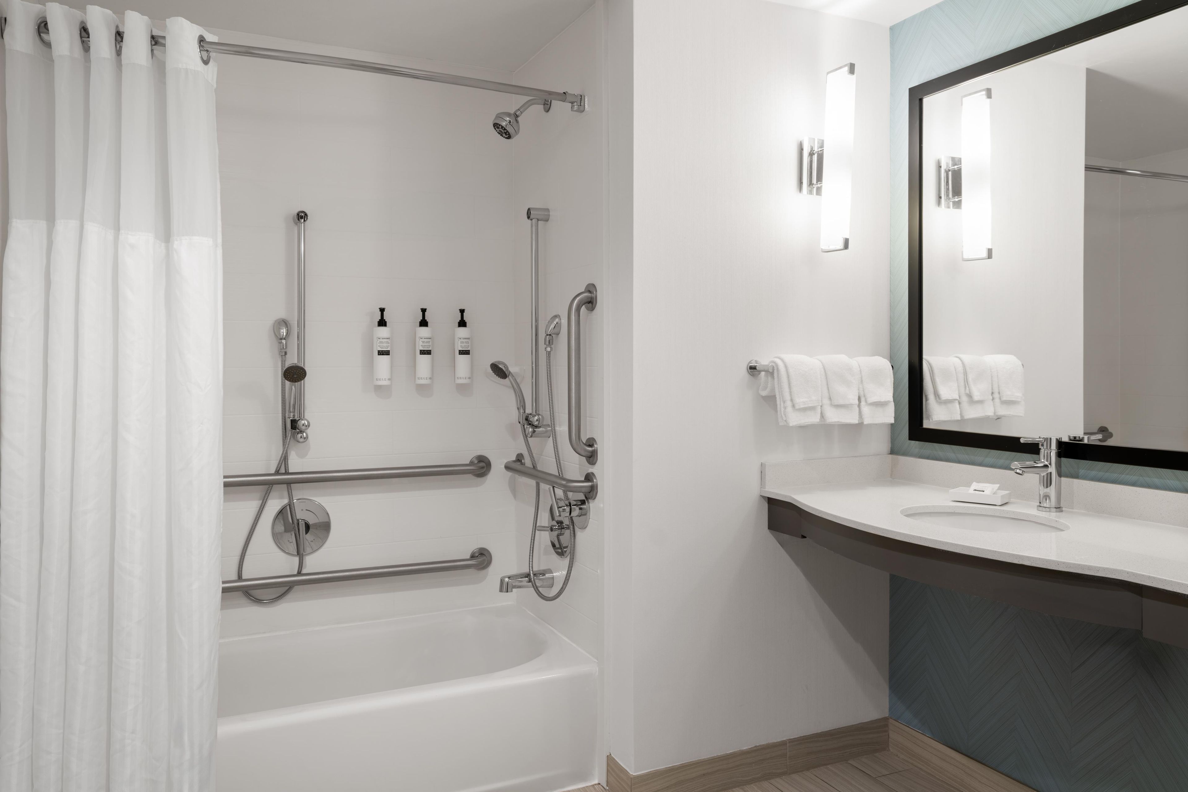 Ein modernes Badezimmer mit einer Badewanne, einer Dusche und einem Waschtisch mit Spiegel.