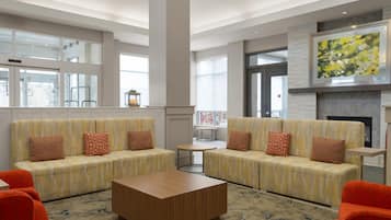 A modern lobby with two sofas, a coffee table, and a fireplace.