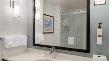 A modern bathroom with a large mirror, a sink, and a shower.