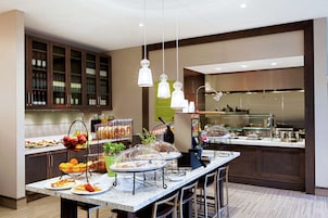 A modern kitchen with a marble countertop, stainless steel appliances, and a variety of food items displayed on the counter.