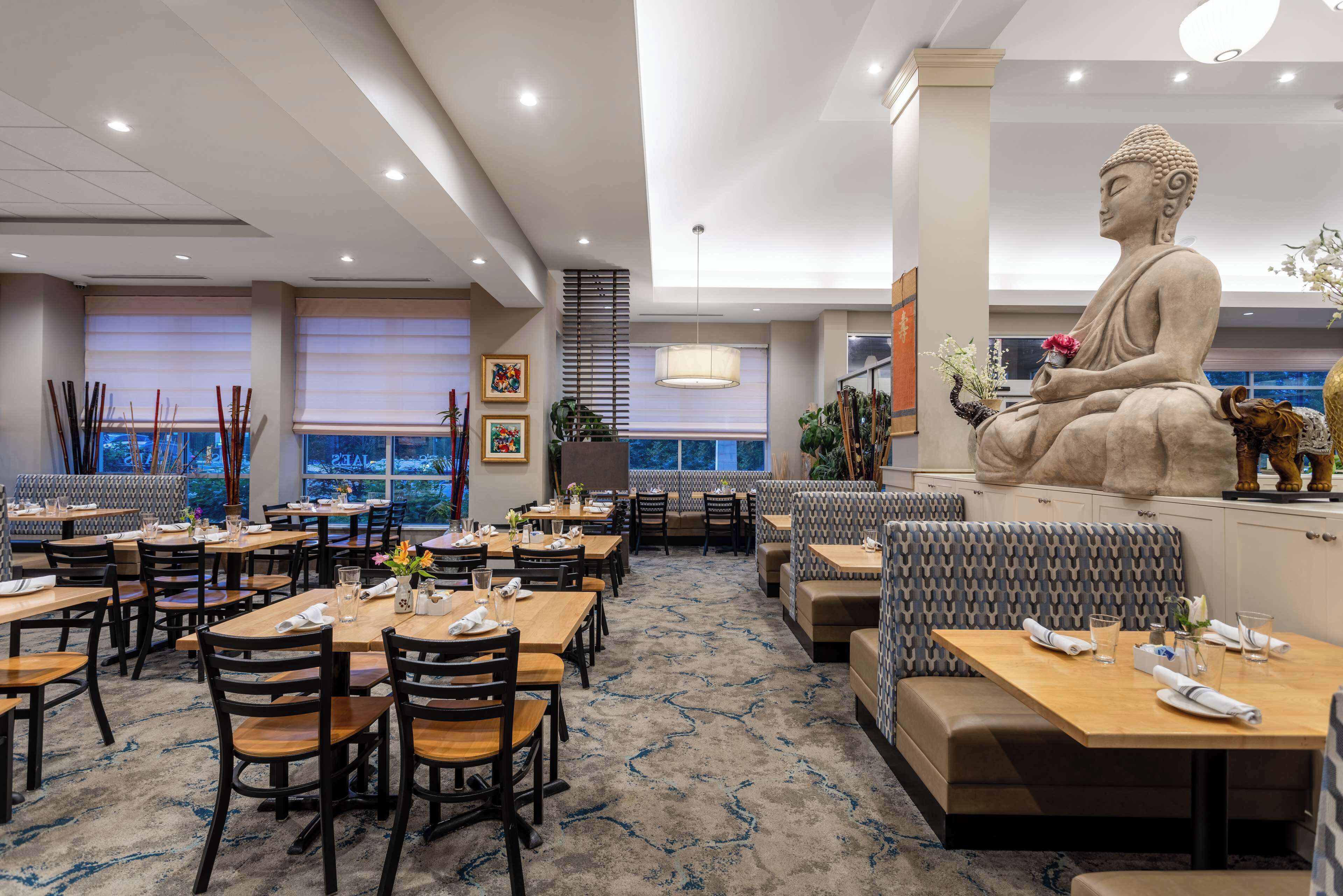 Un ristorante con diversi tavoli, posti a sedere e una grande statua di Buddha.