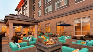 Une terrasse d’hôtel avec des sièges en plein air et un foyer.
