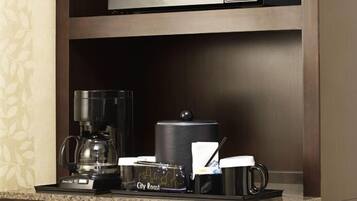 Un coin café équipé d’une machine à café, d’un mousseur à lait, d’une cafetière, d’une tasse et d’un porte-serviettes.