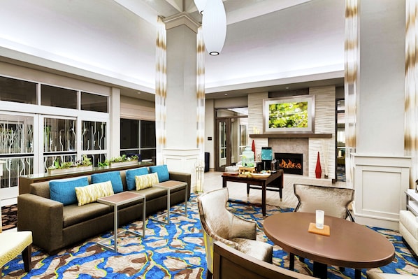 A spacious living room with a large sofa, a coffee table, and a fireplace. - Hilton Garden Inn Lenox Pittsfield (Pittsfield)