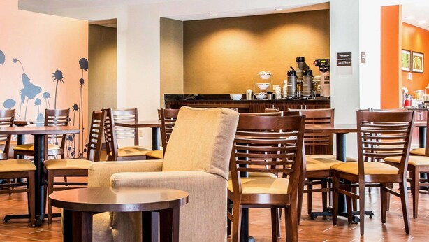 Un vestíbulo de hotel con varias zonas de estar, una estación de café y un mostrador de recepción.