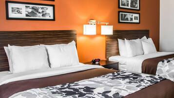 Una habitación de hotel con dos camas, una mesita de noche con un reloj y cuadros enmarcados en la pared.
