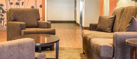 A hotel lobby with two sofas, a coffee table, and a lamp.