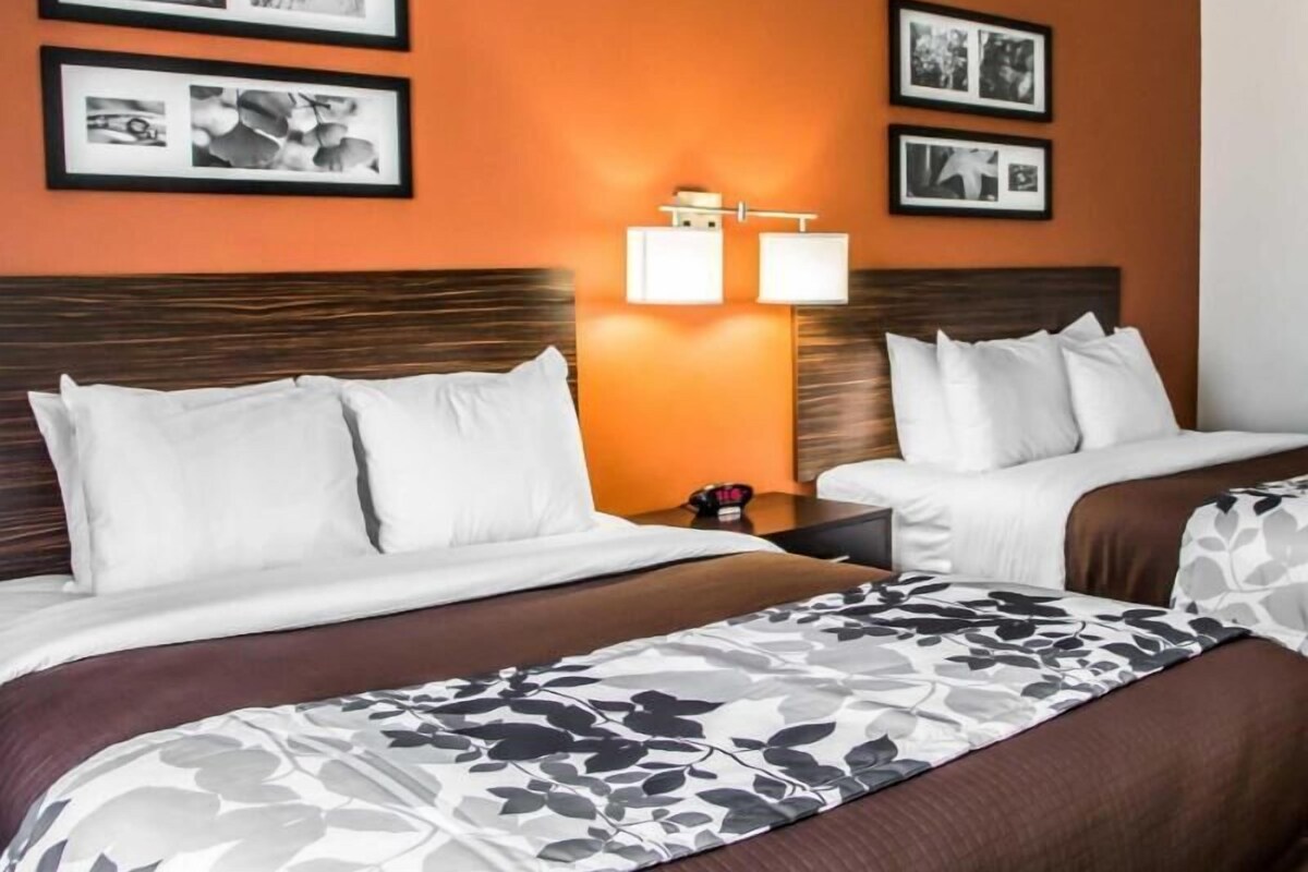 Une chambre d’hôtel avec deux lits, une table de chevet et des lampes fixées au mur.