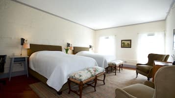 A hotel room with two beds, a desk, a chair, and a small table.