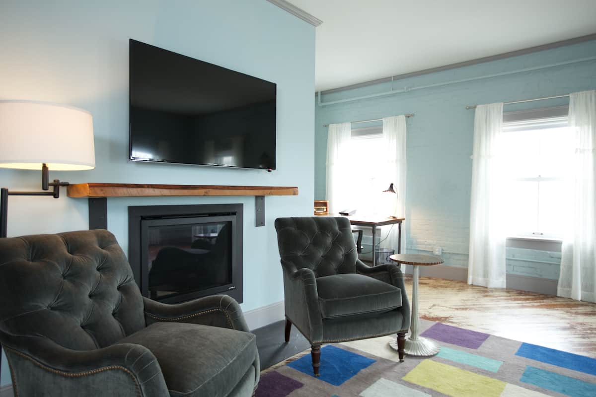 A living room with a fireplace, a television mounted above it, and two armchairs.