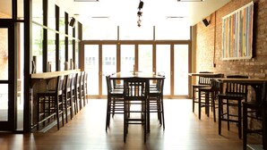 A restaurant with a large open dining area, wooden tables and chairs, and a brick wall with a colorful mural. - Hotel On North (Pittsfield)