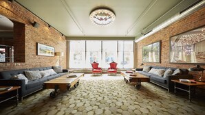A spacious room with a large window, a brick wall, a sofa set, and a patterned carpet. - Hotel On North (Pittsfield)