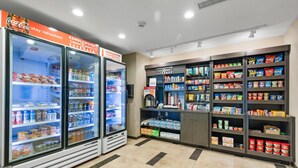 A self-service beverage station with Coca-Cola and Candlewood Cupboard products, and a snack shelf stocked with various items.
