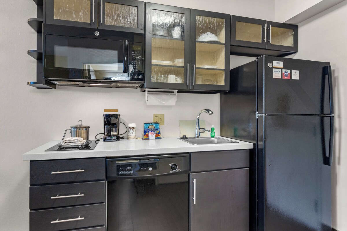 A compact kitchen with a dishwasher, a refrigerator, and a microwave.