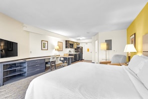 A hotel room with a large bed, a desk with a chair, a TV, and a kitchenette. - Candlewood Suites Erie by IHG (Erie)