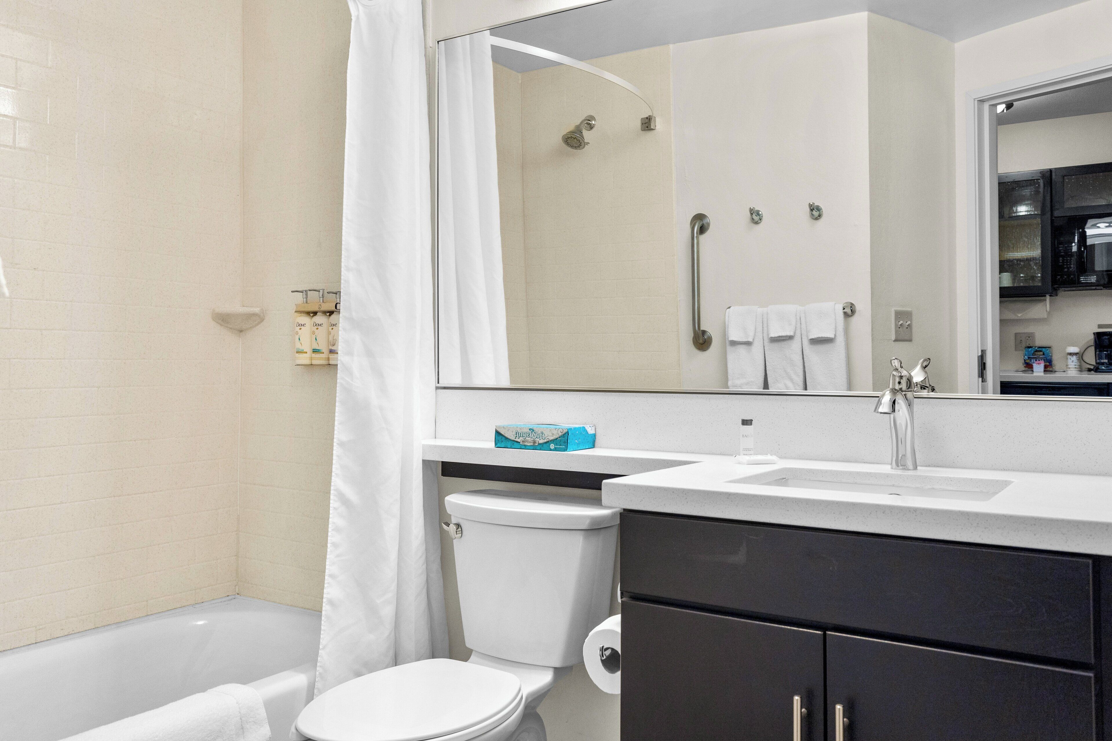 A modern bathroom with a bathtub, toilet, sink, and a large mirror.