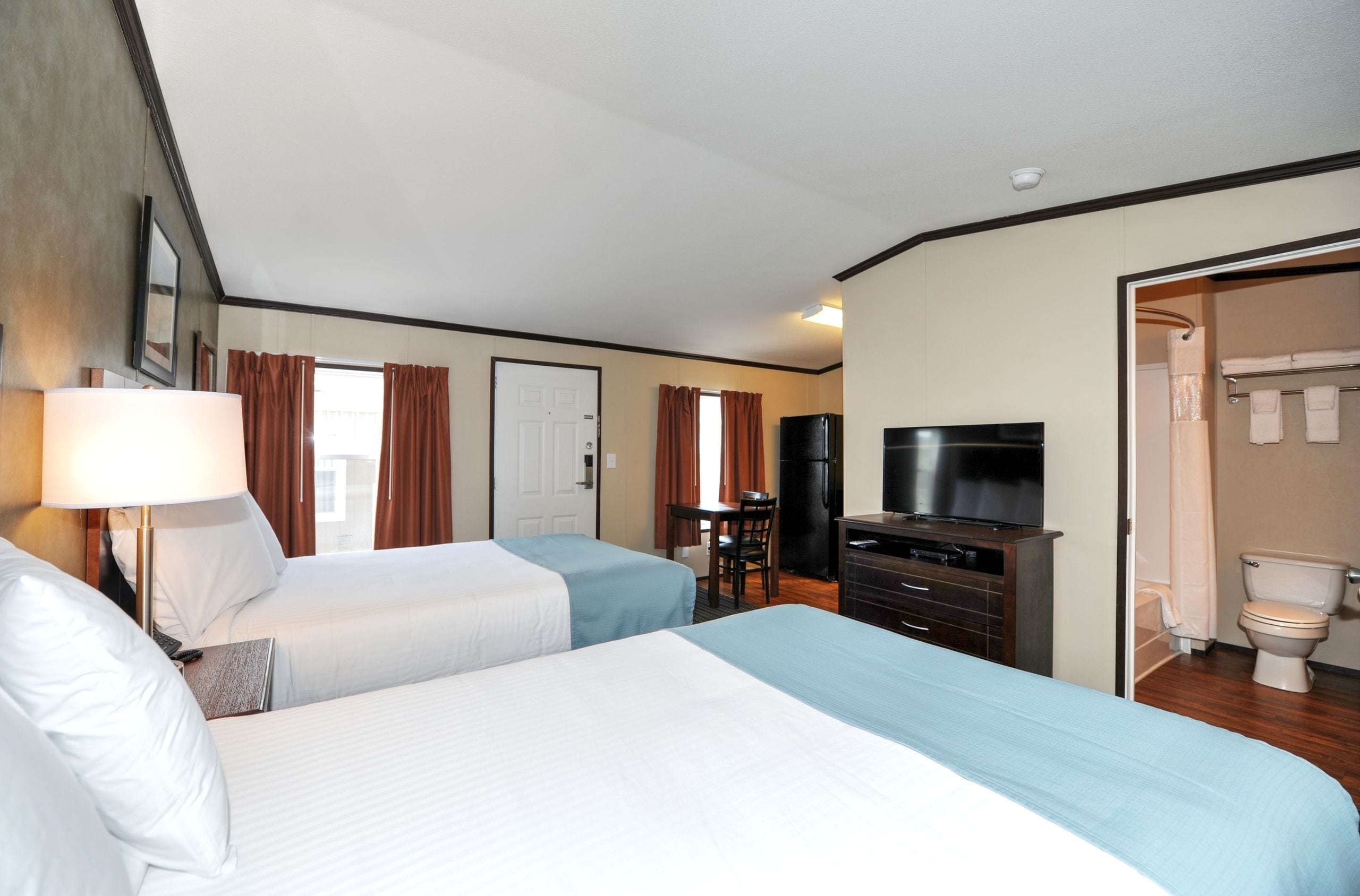 Una habitación de hotel con dos camas, un escritorio, televisión y baño.