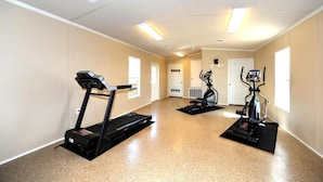 Uma sala de ginástica com esteiras e uma máquina elíptica.