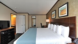 Quarto de hotel com uma cama grande, televisão, escrivaninha e espelho.