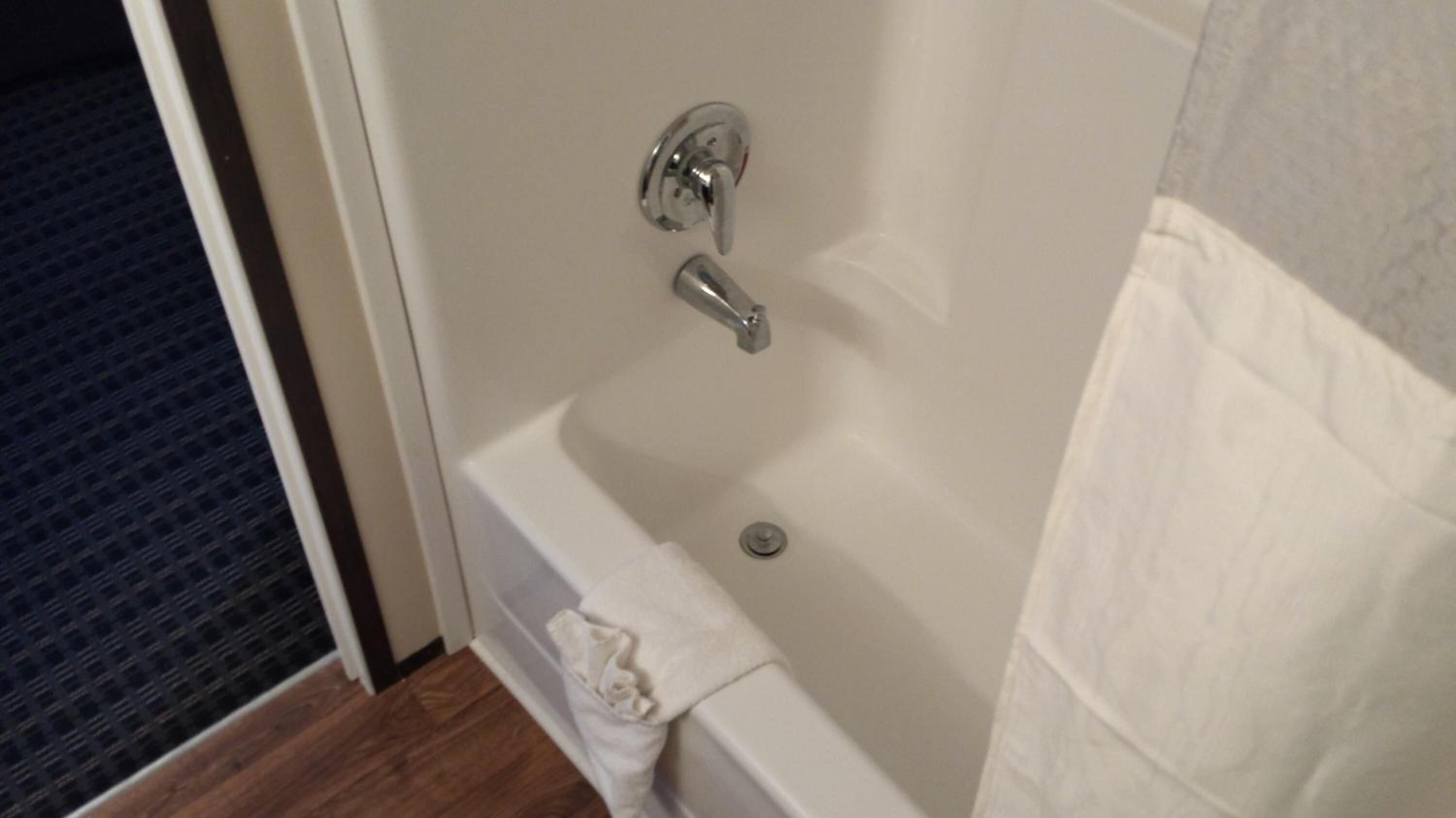 A bathtub with a chrome faucet and a drain.