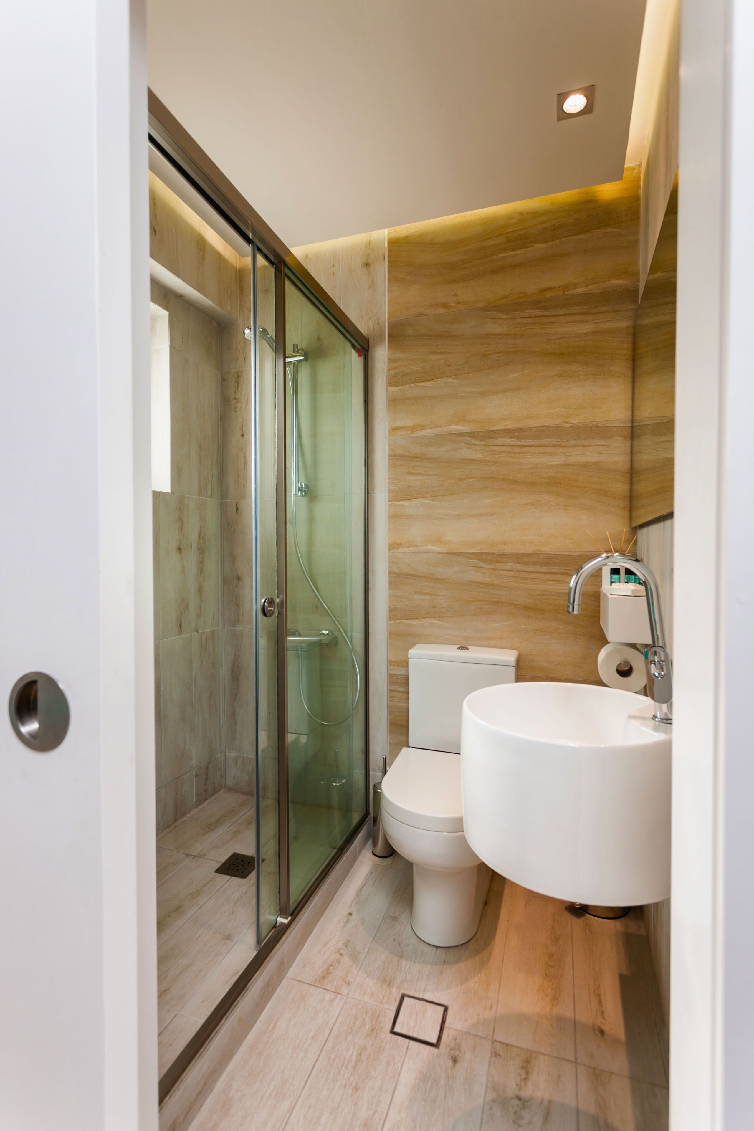 A modern bathroom with a glass-enclosed shower, a toilet, and a large sink.