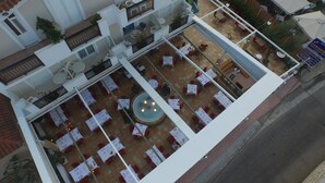 Un área de comedor al aire libre con varios niveles, mesas, sillas, una fuente central y una zona de bar.