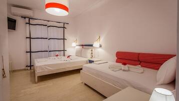 A hotel room with two beds, a red-striped headboard, bedside lamps, and a ceiling light.