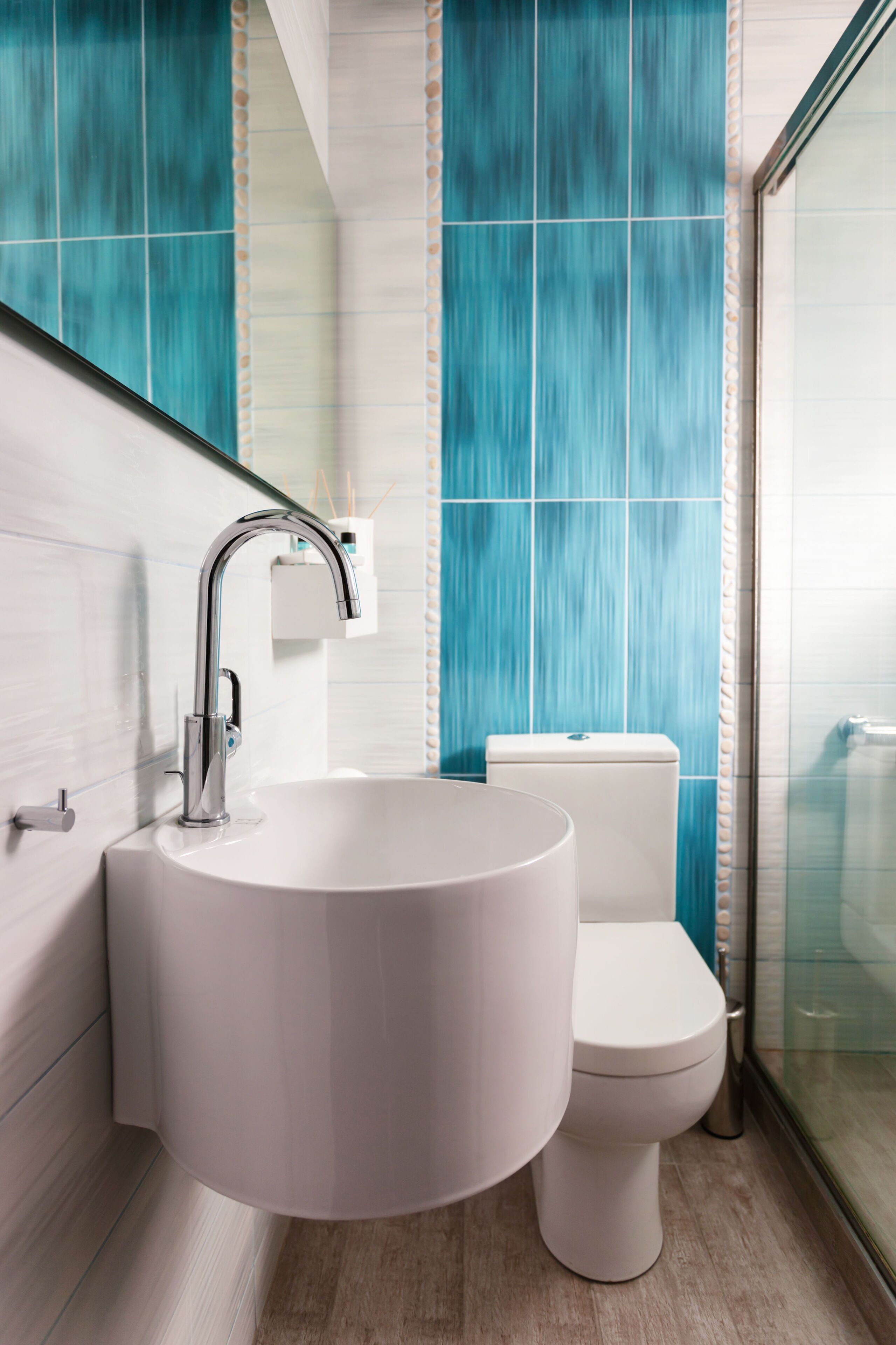 A modern bathroom with a white sink, chrome faucet, and a toilet.