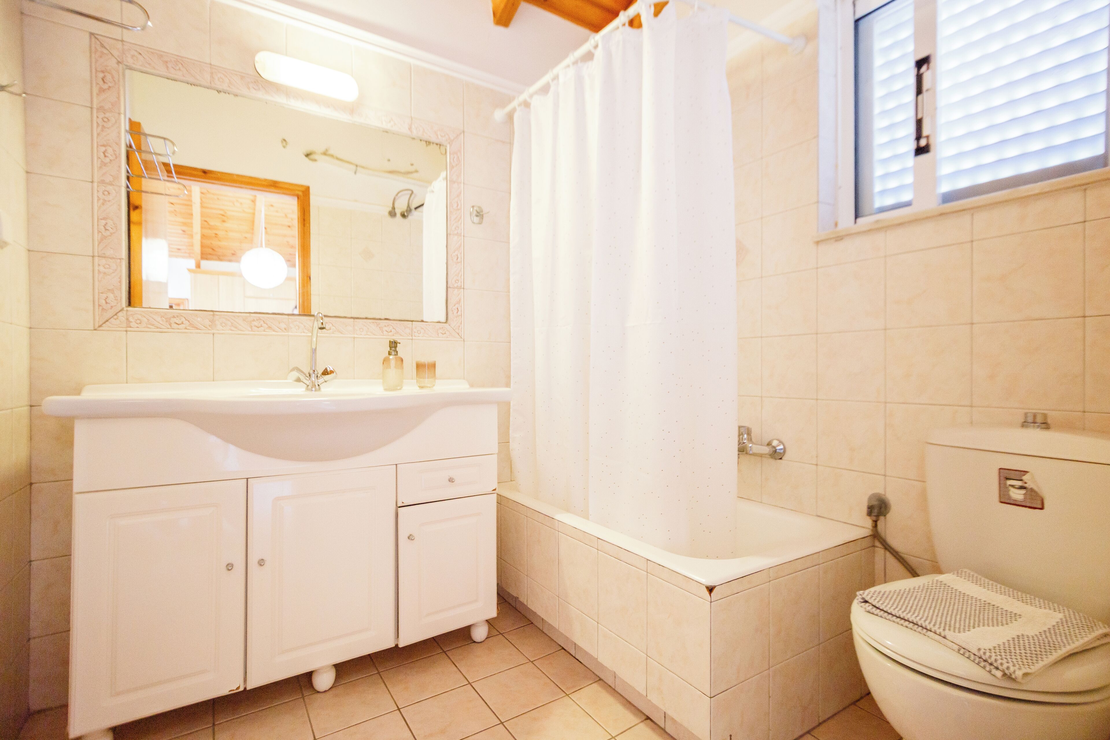 A bathroom with a white sink, mirror, and toilet.