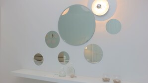 Una pared con varios espejos circulares de distintos tamaños y un estante blanco con adornos.