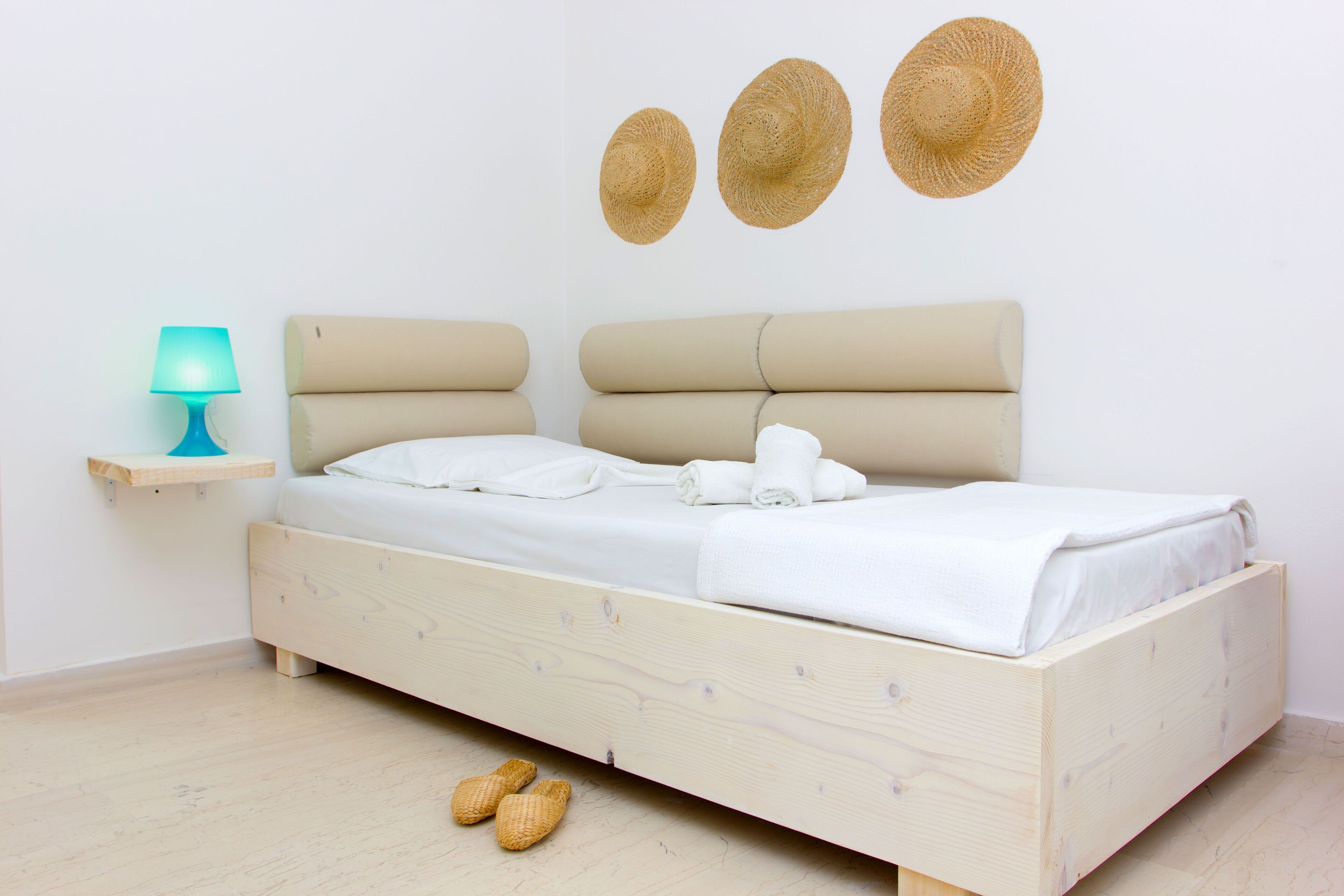 A bedroom with a wooden bed, a bedside lamp, and three wall-mounted hats.