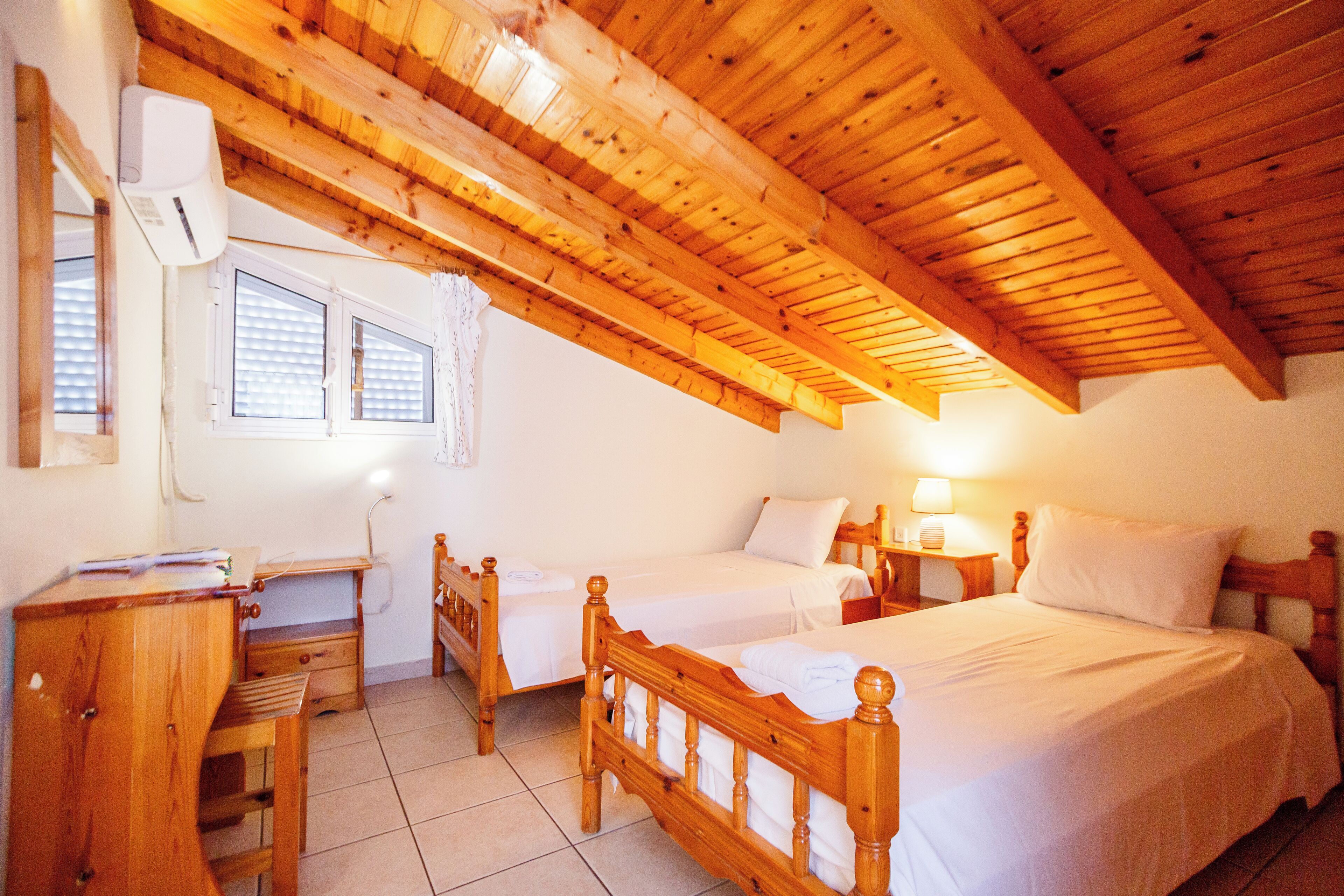 Une chambre à coucher avec deux lits en bois, un bureau et une chaise.
