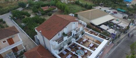 An aerial view of a residential area with a two-story house featuring a rooftop terrace with outdoor seating.